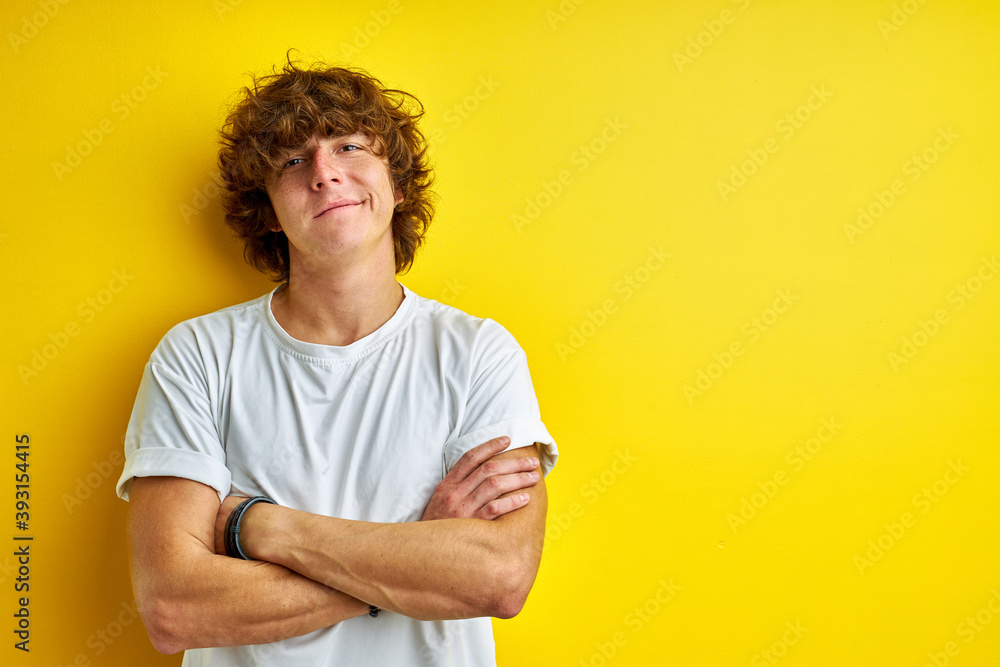 curly guy with long har look at camera, stand with crossed arms posing isolated on yellow background curly guy with long har look at camera, stand with crossed arms posing isolated on yellow background