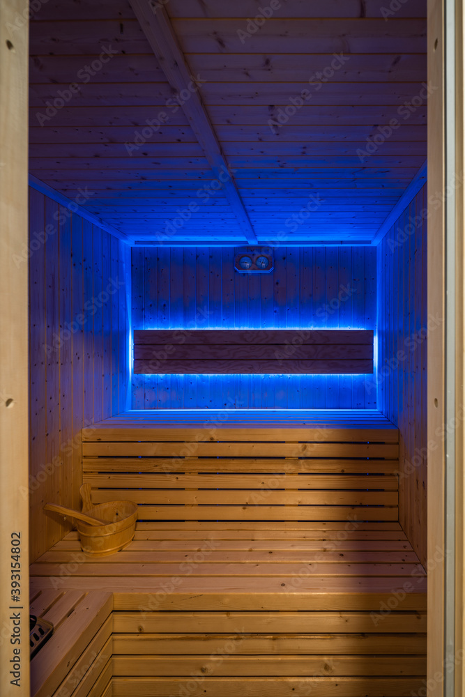 Detail of traditional sauna with wooden interior and bench illuminated by ultraviolet lamp Detail of traditional sauna with wooden interior and bench illuminated by ultraviolet lamp