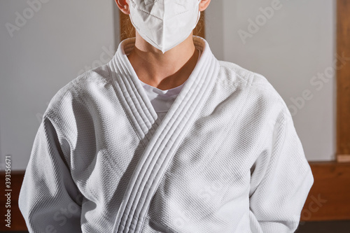 Cropped unrecognizable person with a white kimono and a mask indoors photo