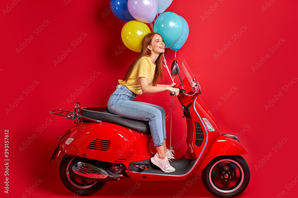 portrait of redhead smiling female on motorcycle, young female delivers bright air balloons to clients, drive red bike portrait of redhead smiling female on motorcycle, young female delivers bright air balloons to clients, drive red bike