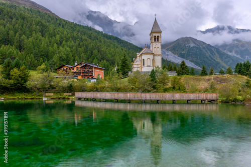 View of Solda, South Tyrol, Italy, its parish church on the lake, with the Ortler mountains in the background