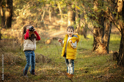 cute boy and girl 4 years old play with an old film camera and take pictures of each other