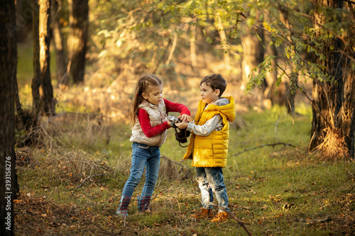 cute boy and girl 4 years old play with an old film camera and take pictures of each other