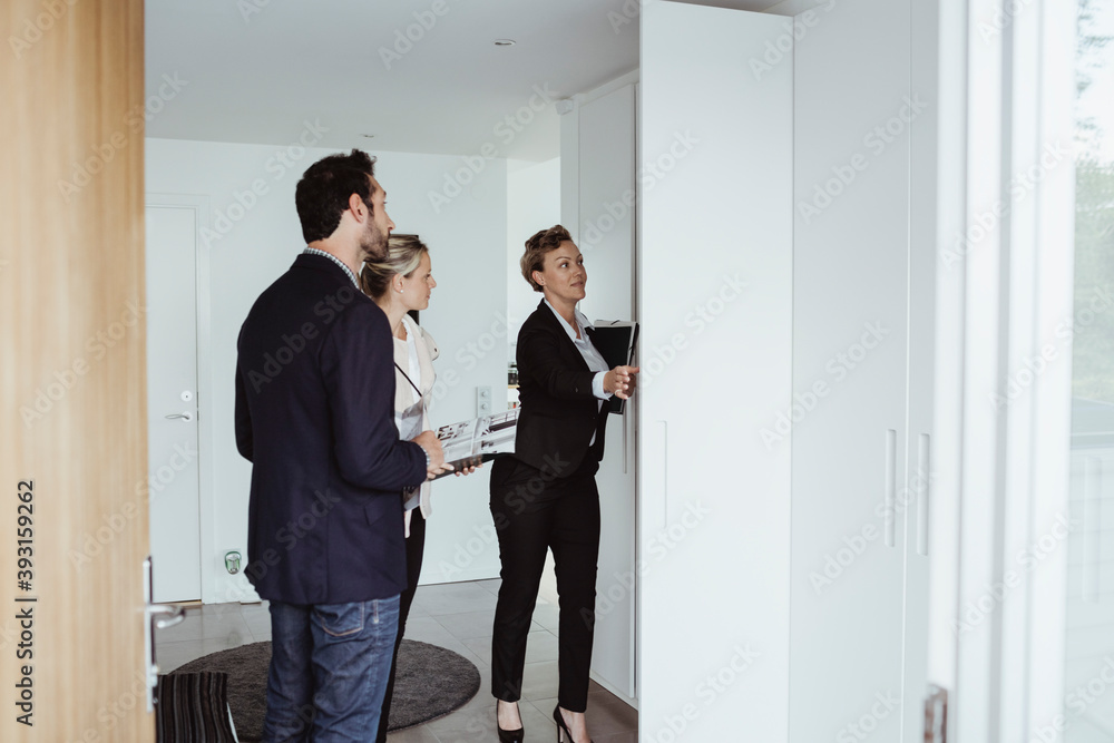 Real estate agent showing property to couple at new house Real estate agent showing property to couple at new house