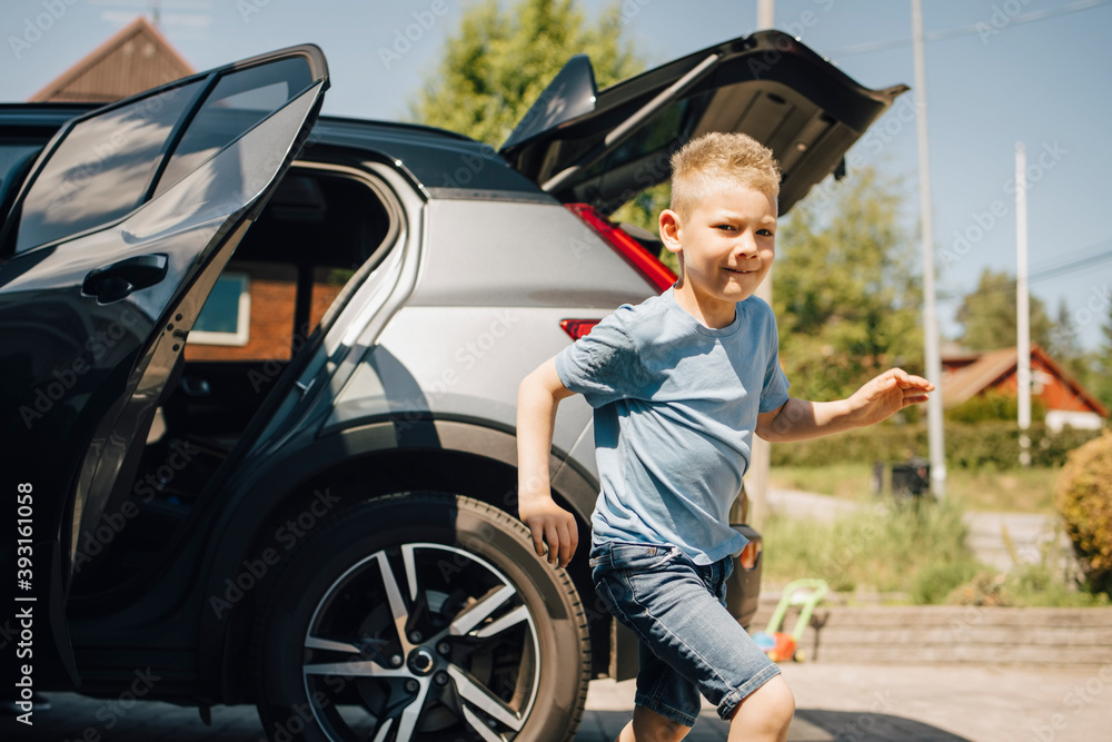 Smiling boy running against car during sunny day Smiling boy running against car during sunny day