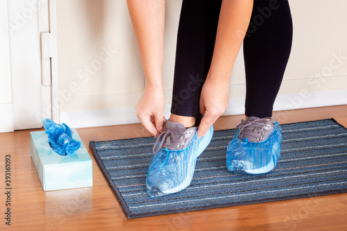 Close up on a woman wearing shoes cover. Woman walking in the house with shoes cover on. Hygienic equipment for house or work places. Overshoes and health protection. Concept of sanitizing environment photo