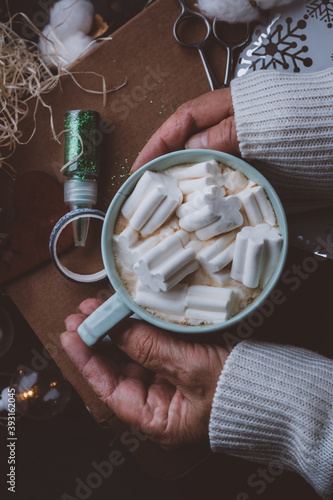 elderly hands holding a Cup of coffee and marshmallow Christmas background