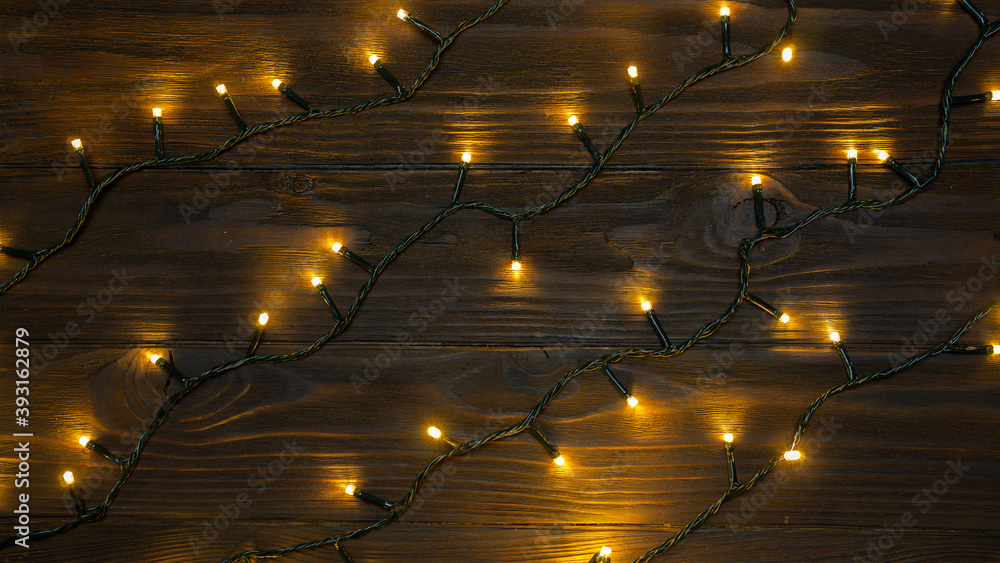 The chain of yellow christmas lights on wooden surface