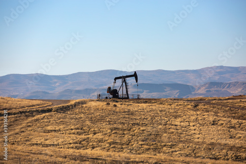 Image of an oil production pump actively operating in daylight in the oilfield