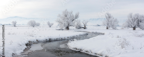 View of creek flowing through snowy landscape