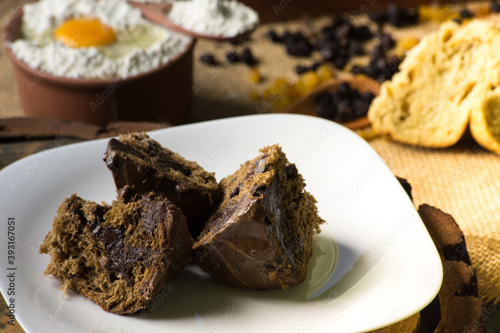chocolate panettone on white plate. rustic table with ingredients chocolate panettone on white plate. rustic table with ingredients