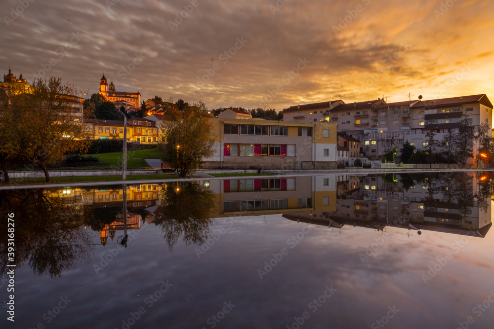 Old buildings and the cathedral of Viseu, during sunset, reflected in a local lake, city of Viseu, Portugal
