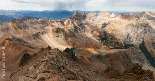 A stunning golden autumn view from the summit of Mount Sneffels of the Blue Lakes and a storm rolling over the distant peaks. Summit views, Blue Lakes, distant storm. 
