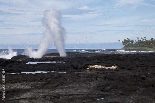 Famous Samoan blowholes at volcanic shore coast, under blue sky photo