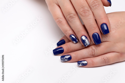Dark blue manicure with silver matte foil under a business card on a white background with a large blanc on the right side on long square nails.