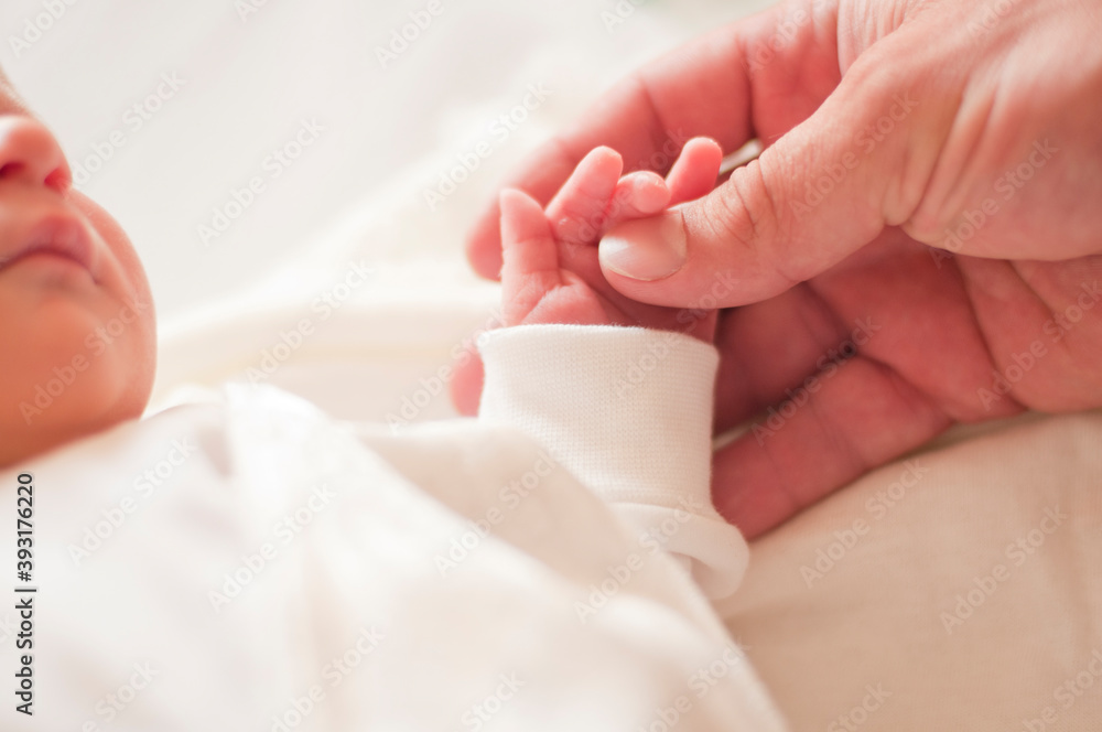 Mom holds a newborn baby by the handle Mom holds a newborn baby by the handle