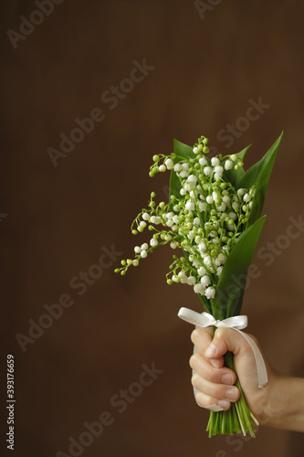On a dark background, a white bouquet of lilies of the valley. 