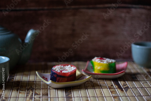 Close up of candy sushi on babmboo mat with tea in background. photo