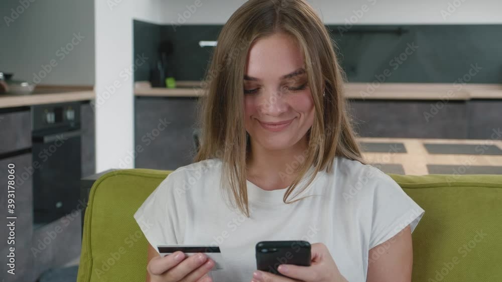 Young woman shopping online on sofa at home. Smiling woman online banking using smartphone shopping online with credit card at home lifestyle. Easy pay using digital gadget. Young woman shopping online on sofa at home. Smiling woman online banking using smartphone shopping online with credit card at home lifestyle. Easy pay using digital gadget.
