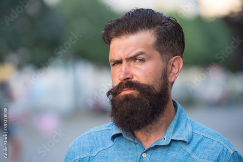 Close-up portrait of serious man model with mustaches and beard in shirt in city.