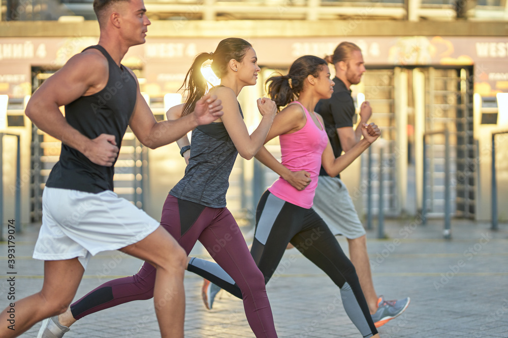 Multi racial team running outdoors on stadium background Multi racial team running outdoors on stadium background
