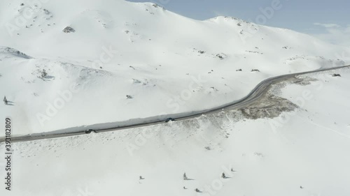 Trucks driving along a snow lined Colorado mountain road in the winter