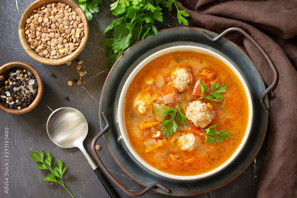 Tomato-lentil soup with meatballs and vegetables on a dark slate table top. Top view flat lay background. Tomato-lentil soup with meatballs and vegetables on a dark slate table top. Top view flat lay background.