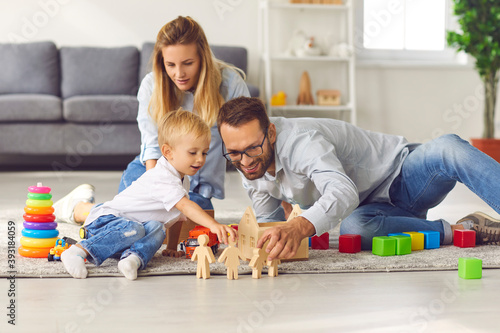 Happy family playing with toys on floor of their living-room, enjoying quality time at home