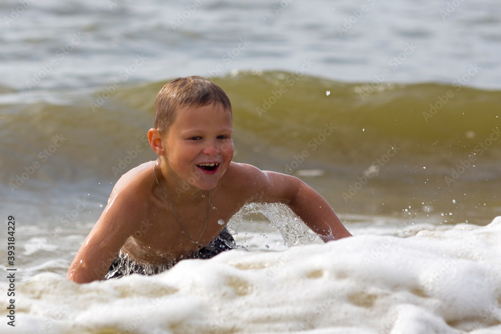 Young cheerful boy having fun at sea waves. Young cheerful boy having fun at sea waves.
