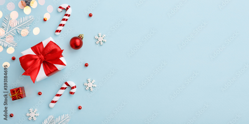 Christmas gift box with red bow and decorations on pastel blue background