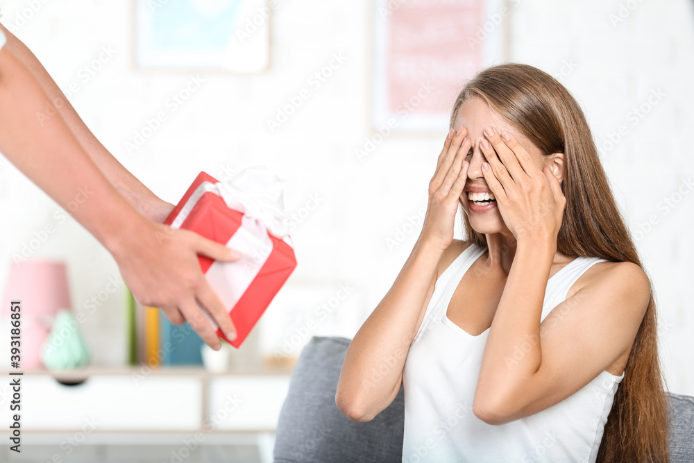 Surprised woman closing eyes and getting gift box from boyfriend Surprised woman closing eyes and getting gift box from boyfriend
