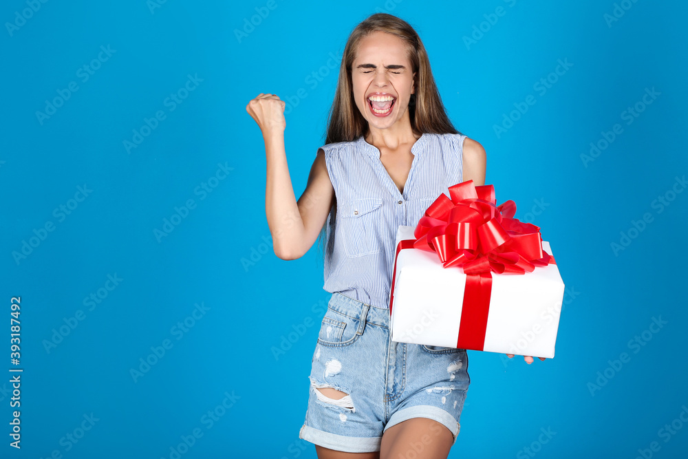Young girl holding gift box on blue background Young girl holding gift box on blue background