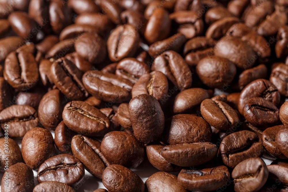 Freshly roasted coffee beans background.Dark roasted coffee beans with scoop on wooden background. Freshly roasted coffee beans background.Dark roasted coffee beans with scoop on wooden background.