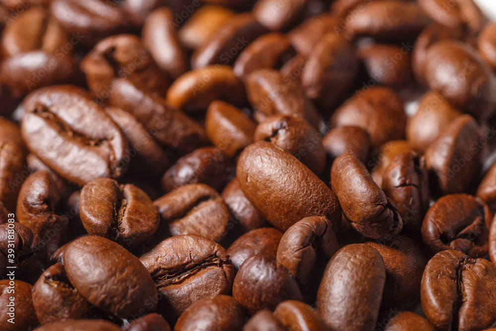 Naklejka premium Freshly roasted coffee beans background.Dark roasted coffee beans with scoop on wooden background.