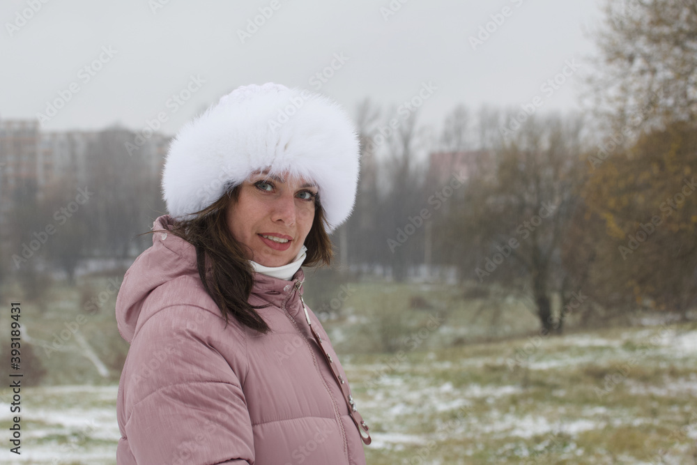 Portrait of a girl in a winter hat. Against the background of the ground covered with the first snow. Portrait of a girl in a winter hat. Against the background of the ground covered with the first snow.