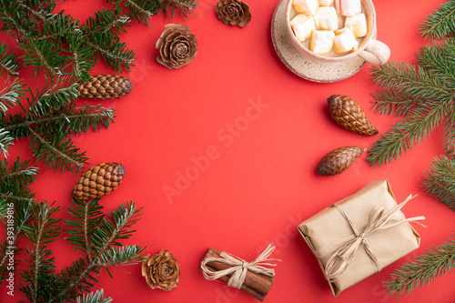 Christmas or New Year frame composition. Decorations, cones, fir and spruce branches, cup of coffee, on a red background. Top view, copy space.