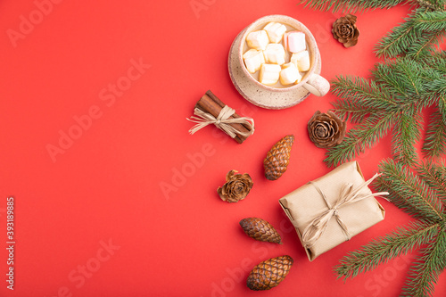 Christmas or New Year composition. Decorations  cones  fir and spruce branches  cup of coffee  on a red background. Top view  copy space.