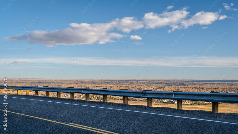 highway at Colorado foothills with a view of plains and city of Fort Collins, fall scenery