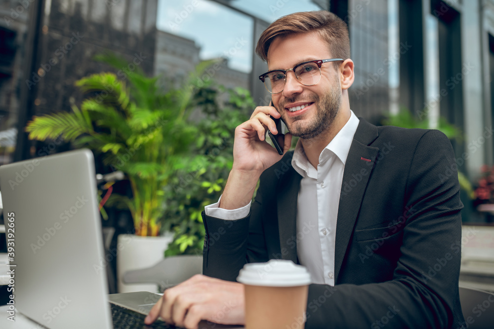 Handsome young businessman talking on the phone and smiling Handsome young businessman talking on the phone and smiling