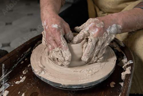 pottery, workshop, ceramics art concept - closeup on male hands sculpt new utensil with a tools and water, man's fingers work with potter wheel and raw fireclay, front close view