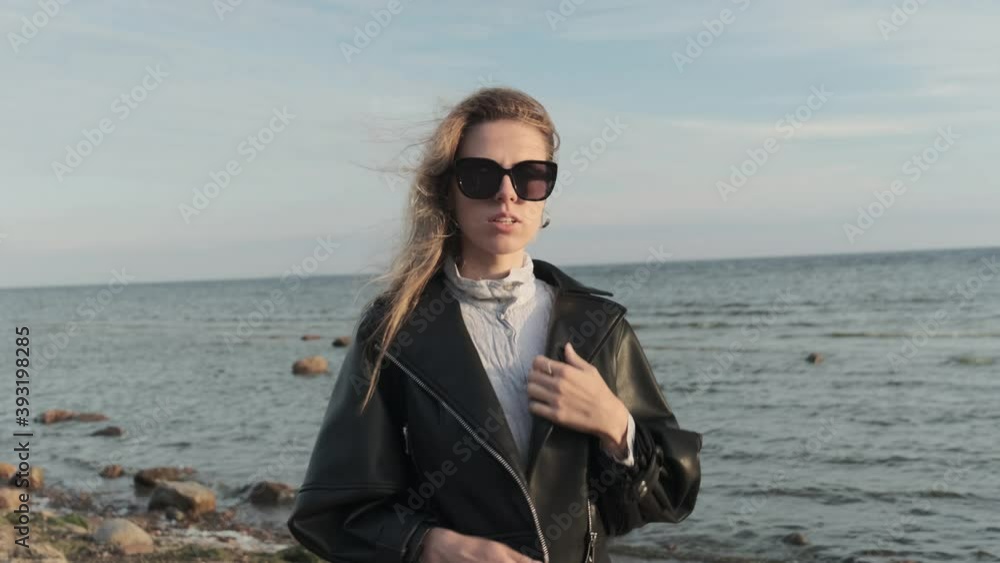 Beautiful young girl in a sunglasses walks in a sea coast, posing, looking at the camera and straightens hair from windy 4k Beautiful young girl in a sunglasses walks in a sea coast, posing, looking at the camera and straightens hair from windy 4k