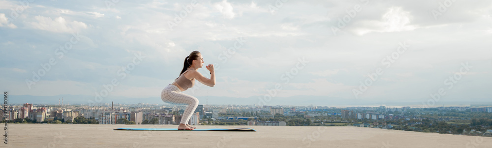 Side view of muscular young woman with long ponytail in sunny morning. Gorgeous girl practicing exercises, warming up lower body on city background