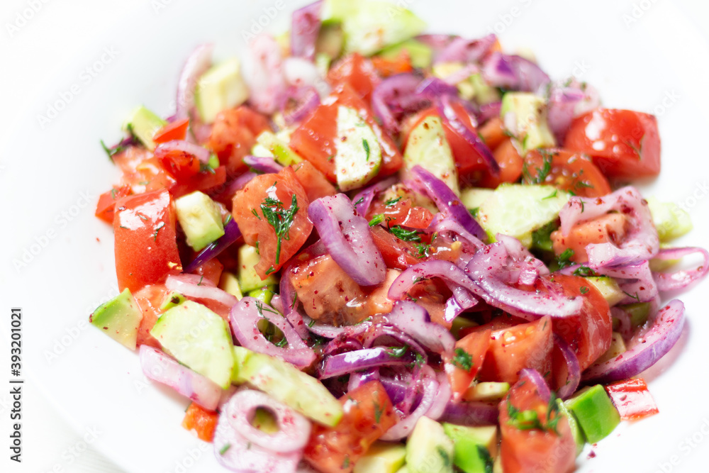 vegetable salad with  red onion, tomato, cucumber, avocado, dill, sumach, paprika, olive oil  in white bowl