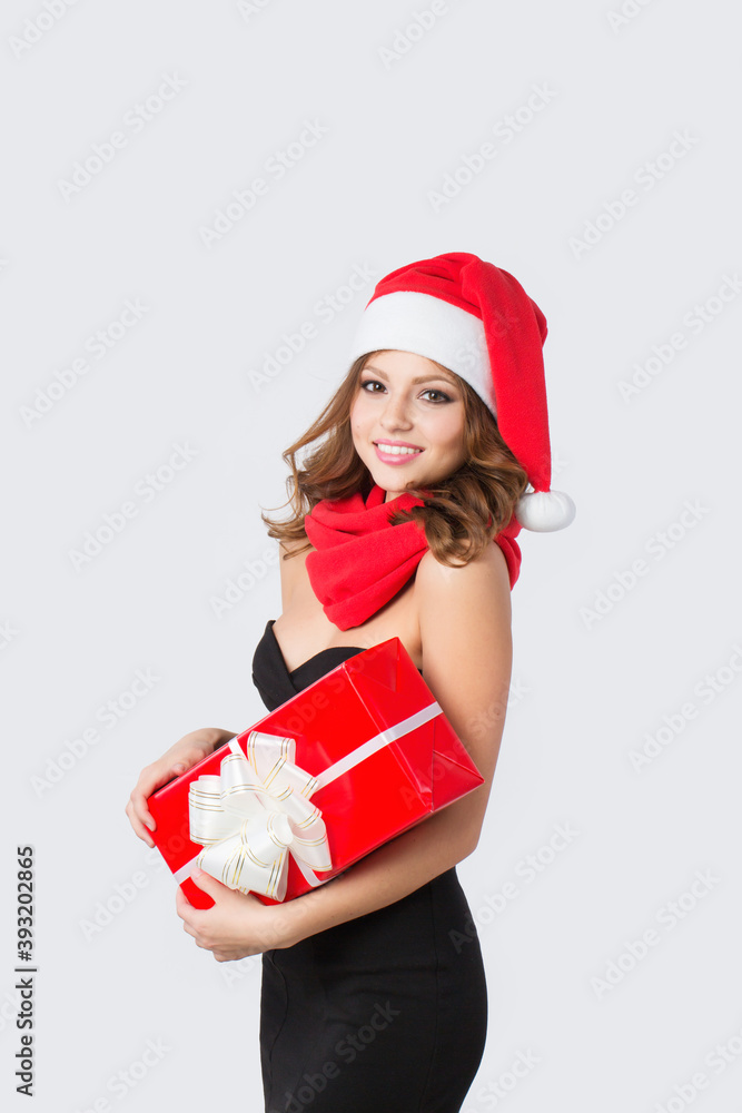 Beautiful smiling woman in Santa hat with a red gift box in her hands on a white. Beautiful smiling woman in Santa hat with a red gift box in her hands on a white.