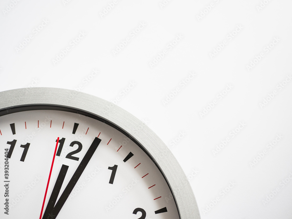 Close up of a ticking clock on white background, pointing a few minutes past midnight, copyspace Close up of a ticking clock on white background, pointing a few minutes past midnight, copyspace