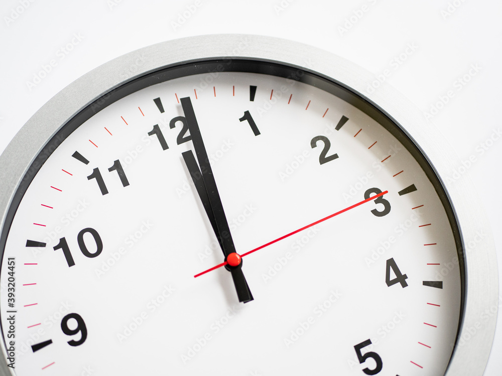 Close up of a ticking clock on white background, pointing a few minutes past midnight, copyspace Close up of a ticking clock on white background, pointing a few minutes past midnight, copyspace