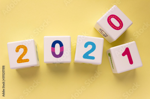 Cubes with colorful numbers on a yellow background. Year change concept, from 2020 to 2021. Digit 1 pops out digit 0. New year, calendar