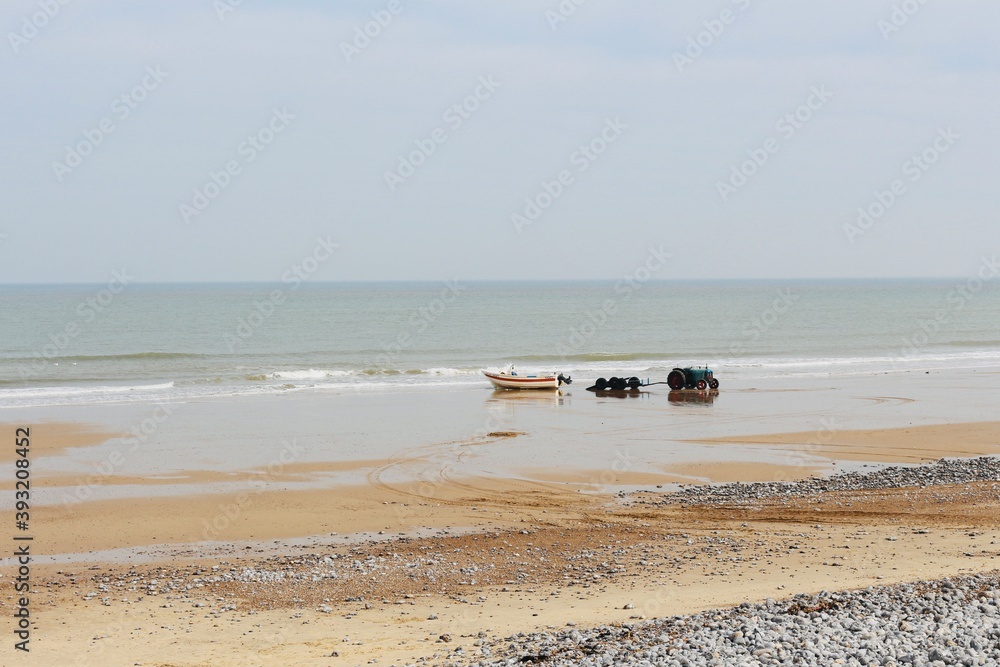 North sea view of the beach in a sunny spring day, boats on the shore waives crashing on north sea beach in England, Norfolk, UK North sea view of the beach in a sunny spring day, boats on the shore waives crashing on north sea beach in England, Norfolk, UK