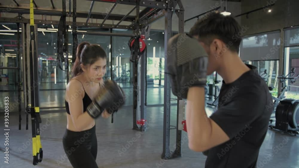Fitness concept. Woman fighter ready to throw a punch with trainer teacher holding pads for boxing session. 4k Resolution. Fitness concept. Woman fighter ready to throw a punch with trainer teacher holding pads for boxing session. 4k Resolution.