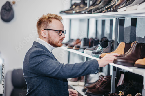 fashionable male stylist in glasses and a jacket chooses shoes in the store.